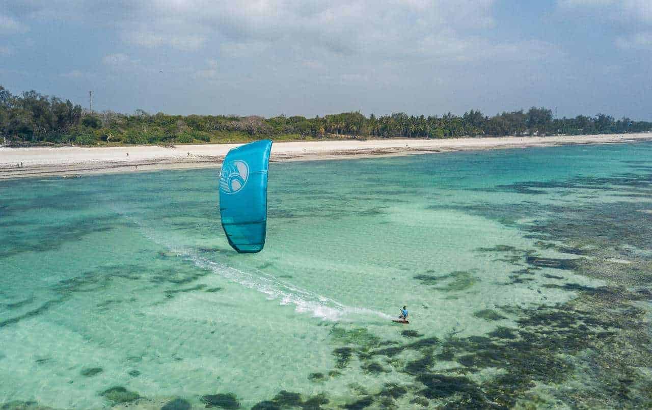 Kitesurfing kites and a dhow over shallow turquoise water in Watamu, Kenya